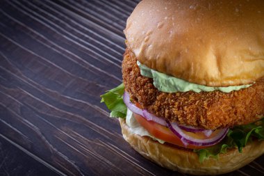 Marullu tavuk burger, domates, mor soğan ve ahşap masada el yapımı mayonez. Lezzetli.