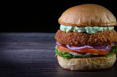 Marullu tavuk burger, domates, mor soğan ve ahşap masada el yapımı mayonez. Lezzetli.