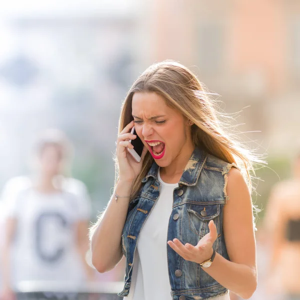 Злой и расстроенный подросток кричит на мобильный телефон — стоковое фото