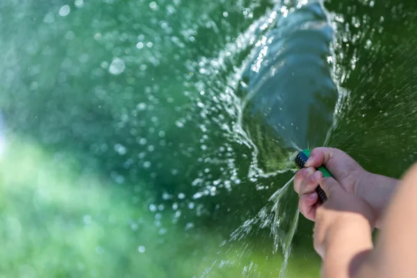 Dítě si hraje s postřikovačem vody na zahradě — Stock fotografie