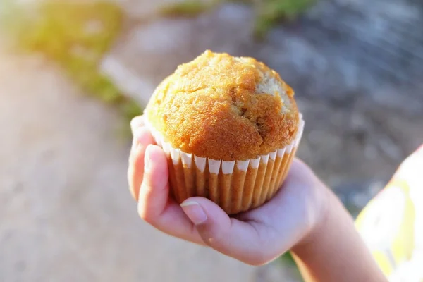 Malá dívka ruka drží muffin ráno — Stock fotografie