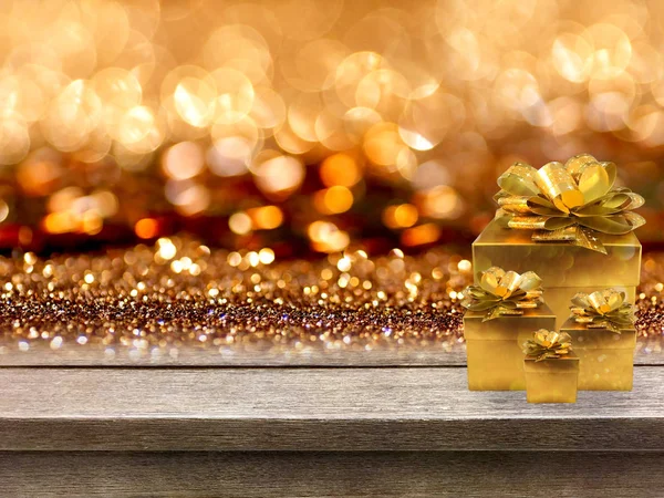 Gold gift boxes and ribbon on wood table, bokeh background