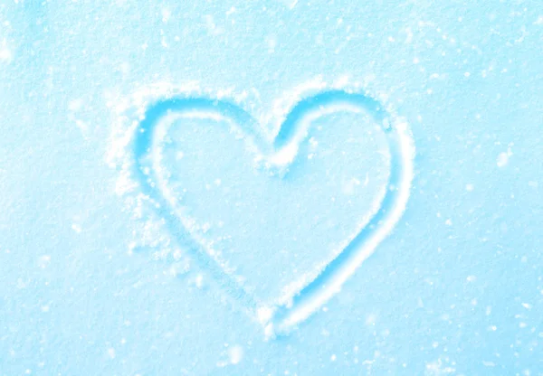 Рука намальована форма серця на свіжому синьому снігу зі снігопадами — стокове фото