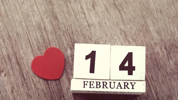 14. února na dřevěná kostka kalendáři, na rozmazané dřevěný stůl kon — Stock fotografie