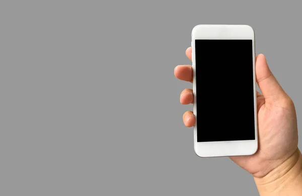 Ręka trzyma puste czarny ekran inteligentny telefon na szarym tle w — Zdjęcie stockowe