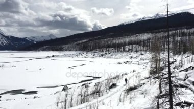 Milli park içinde donmuş gölün çevresinde yürüyen adam