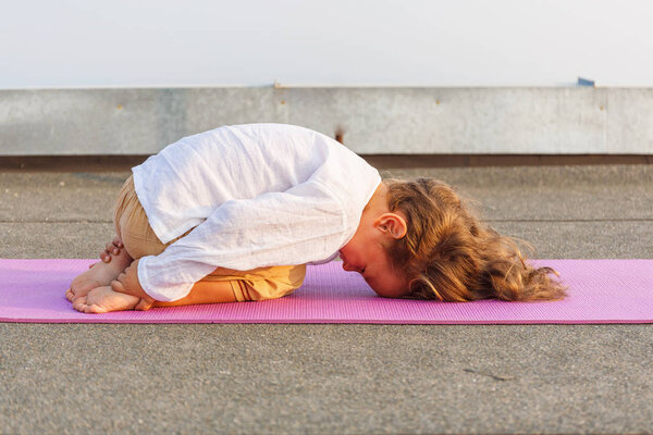 Малыш занимается йогой на крыше
