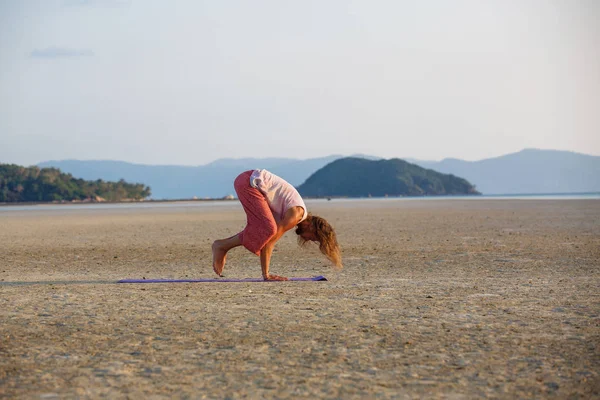 El hombre está haciendo yoga en la playa — Foto de Stock