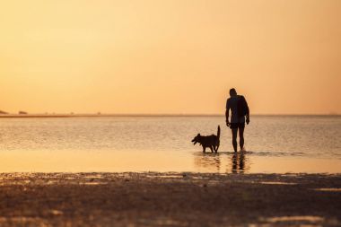 Denizde köpeği olan bir adam.