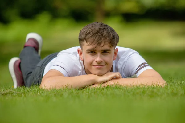 Menino adolescente deitado na grama em um dia de verão — Fotografia de Stock