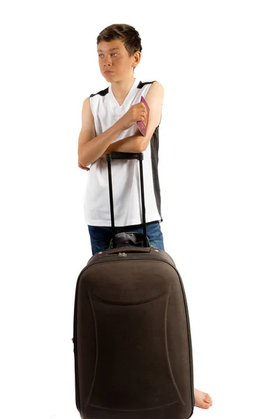 Молодий хлопчик-підліток ізольований на білому чекає з валізою і — стокове фото