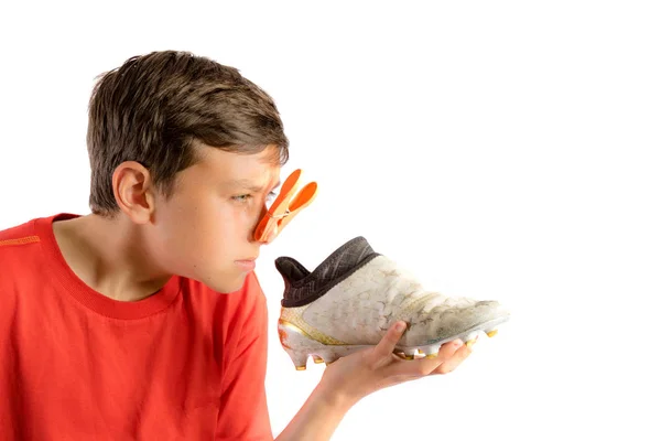 Giovane adolescente isolato su uno sfondo bianco con una scarpa da calcio puzzolente — Foto Stock