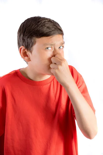 Young teenage boy isolated on a white background holding his nose — Stock Photo, Image