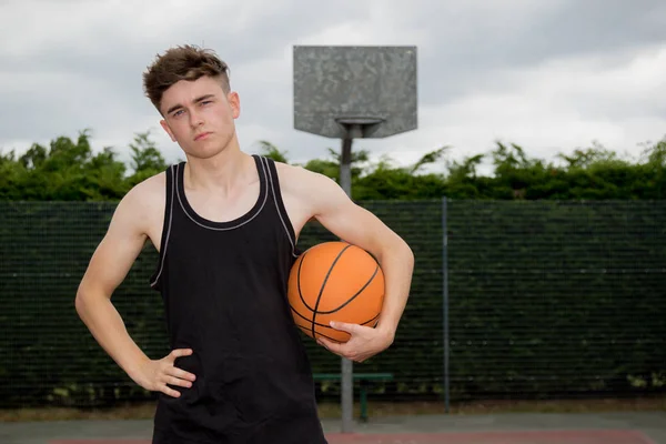 Tonårspojke som innehar en basketboll på en domstol — Stockfoto