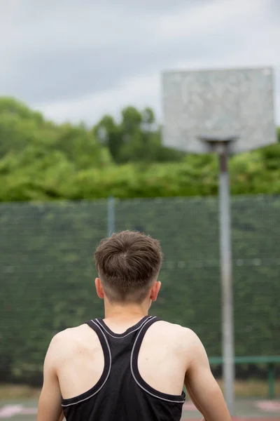Tonårspojke skytte en hoop på en basketplan — Stockfoto