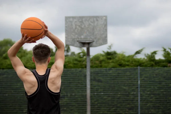 Adolescente atirando um aro em um campo de basquete — Fotografia de Stock