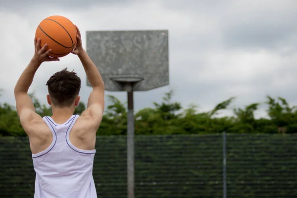 Teenager schießt einen Reifen auf einem Basketballfeld — Stockfoto