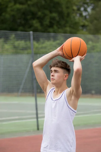 Adolescente atirando um aro em um campo de basquete — Fotografia de Stock