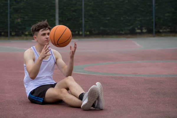 Remaja laki-laki melemparkan bola basket dari satu tangan ke tangan lain di c — Stok Foto
