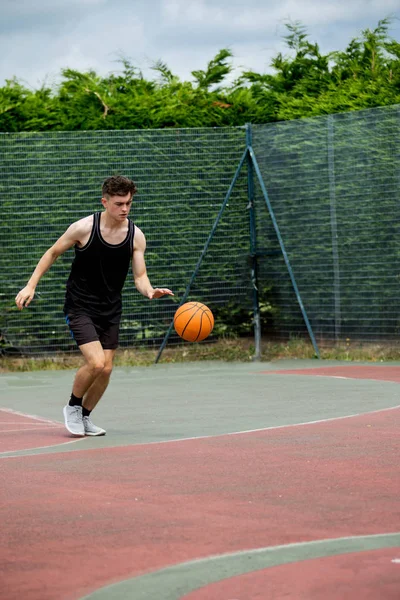 十几岁的男孩，在球场上弹跳篮球 — 图库照片