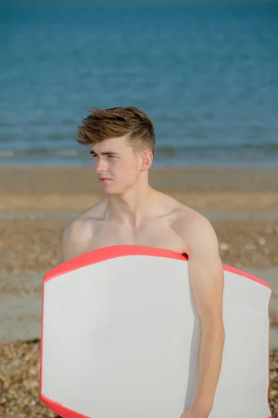 Teenager hält am Strand ein Brett in der Hand — Stockfoto