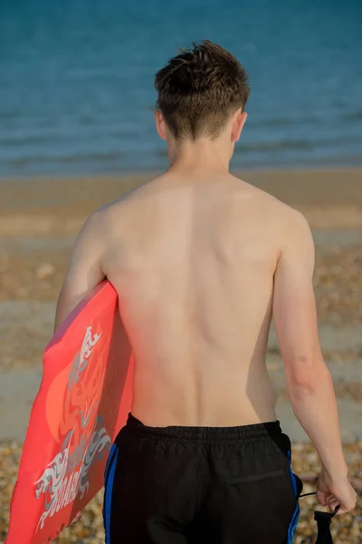 十几岁的男孩在海滩上举行身板子 — 图库照片