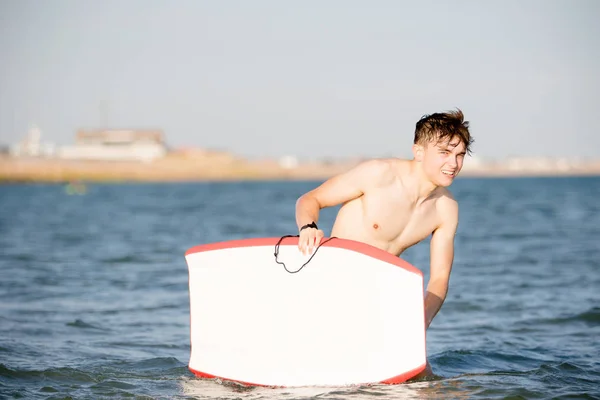 Teenager mit Brett im Meer — Stockfoto