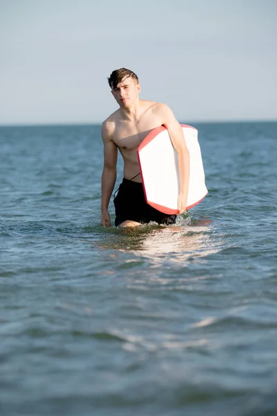 Adolescente ragazzo con una tavola per il corpo in mare — Foto Stock