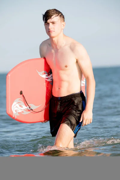 Teenage boy with a body board in the sea — Stock Photo, Image