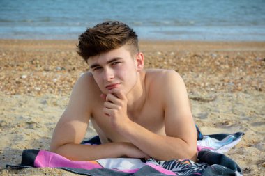 Genç çocuk stoney kumsalda döşeme