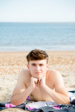 Genç çocuk stoney kumsalda döşeme