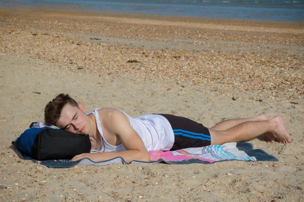 Teenage boy laying on a stoney beach — Stock Photo, Image