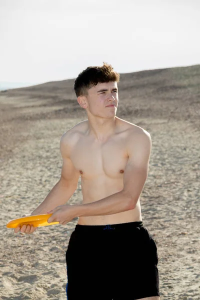 Genç çocuk ile bir frisbee kumsalda oynarken