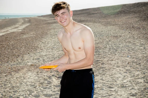 Ragazzo adolescente che gioca con un frisbee su una spiaggia — Foto Stock