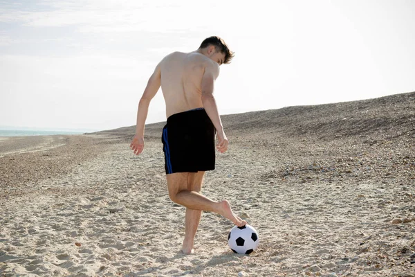 Ragazzo adolescente che gioca con un calcio su una spiaggia — Foto Stock