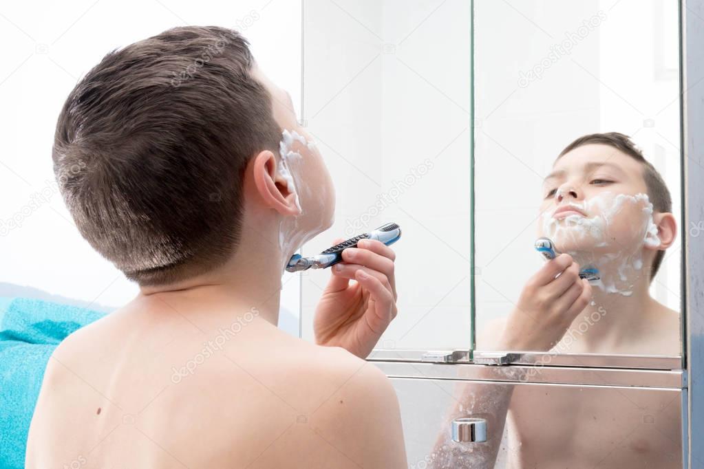 Young teenage boy shaving for the first time