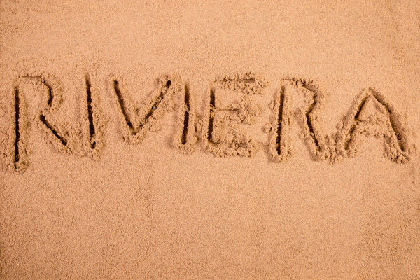 Riviera written in soft wet sand on a beach