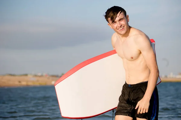 Adolescente com uma placa de corpo no mar — Fotografia de Stock