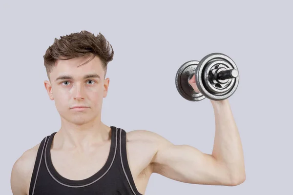 Strong teenage boy exercising by lifting weights — Stock Photo, Image