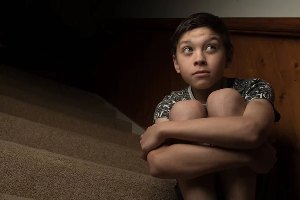Грустный мальчик, сидящий на лестнице — стоковое фото