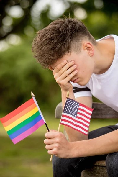 Deprimido adolescente com bandeira dos Estados Unidos e uma bandeira do orgulho — Fotografia de Stock