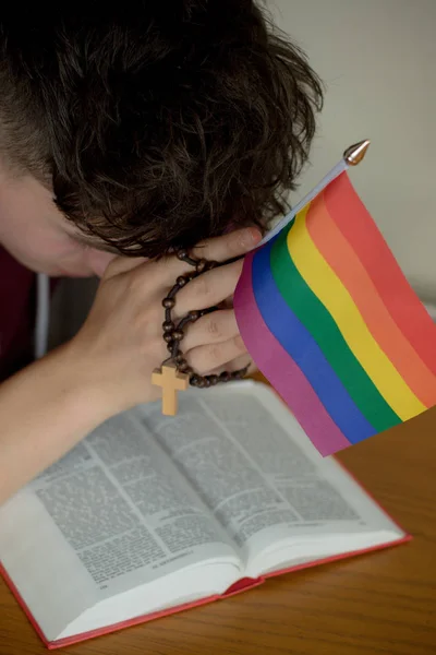 Teenage boy praying with a rosary and a Pride Flag — Stock Photo, Image