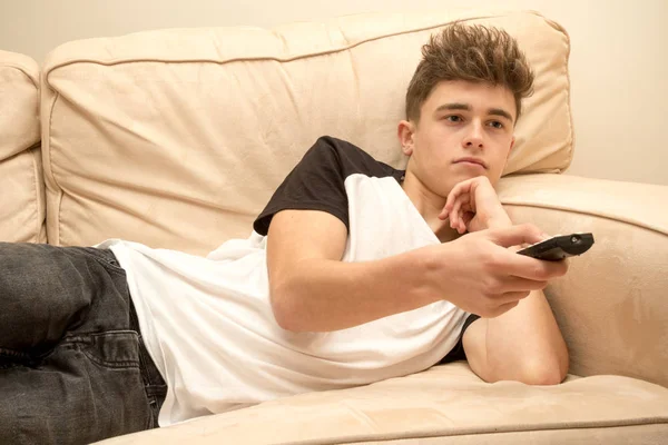 Підліток хлопчик лежить на дивані дивитися телевізор — стокове фото