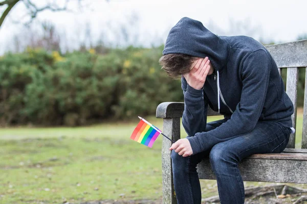 Deprimido adolescente menino segurando uma bandeira de orgulho — Fotografia de Stock
