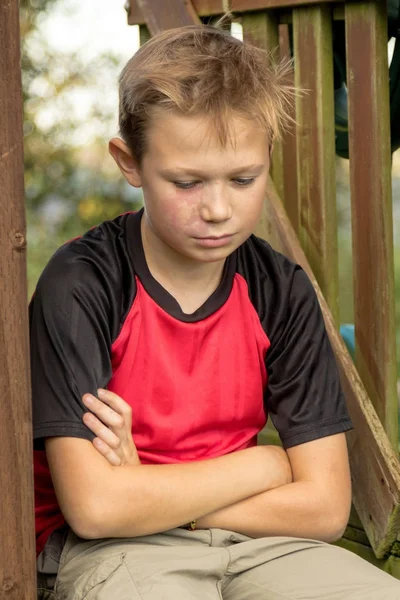 Sad pre-teen boy sitting outside — Stock Photo, Image