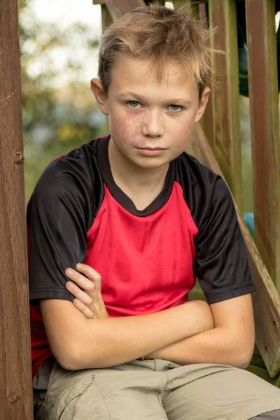 Smutný pre-dospívající chlapec sedí venku — Stock fotografie