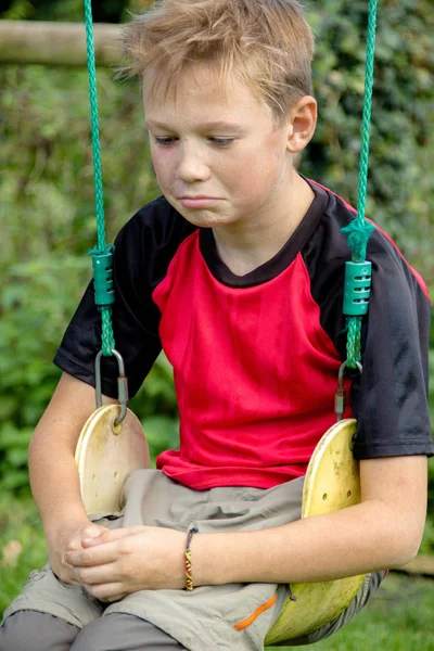 Droevig vooraf tiener jongen zit op een schommel — Stockfoto