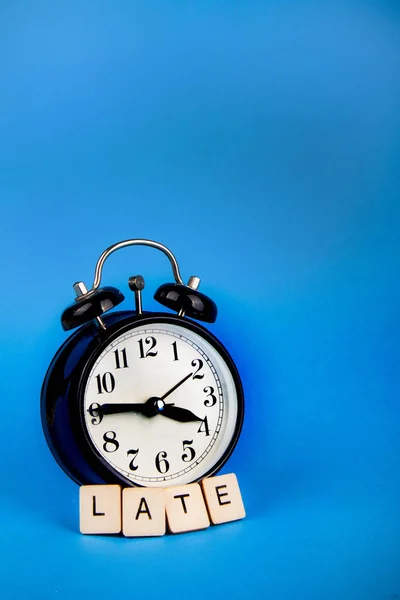 Black alarm clock on a blue background