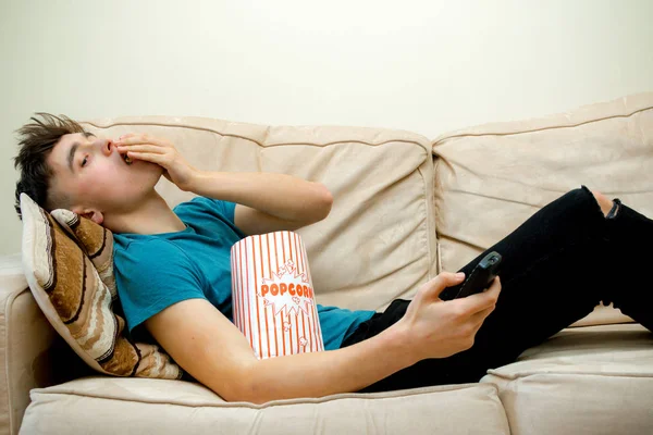 Хлопчик-підліток на дивані їсть попкорн — стокове фото