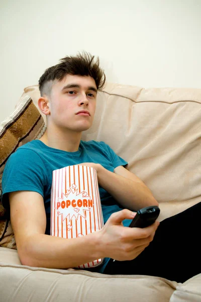 Tiener op een sofa eten popcorn — Stockfoto